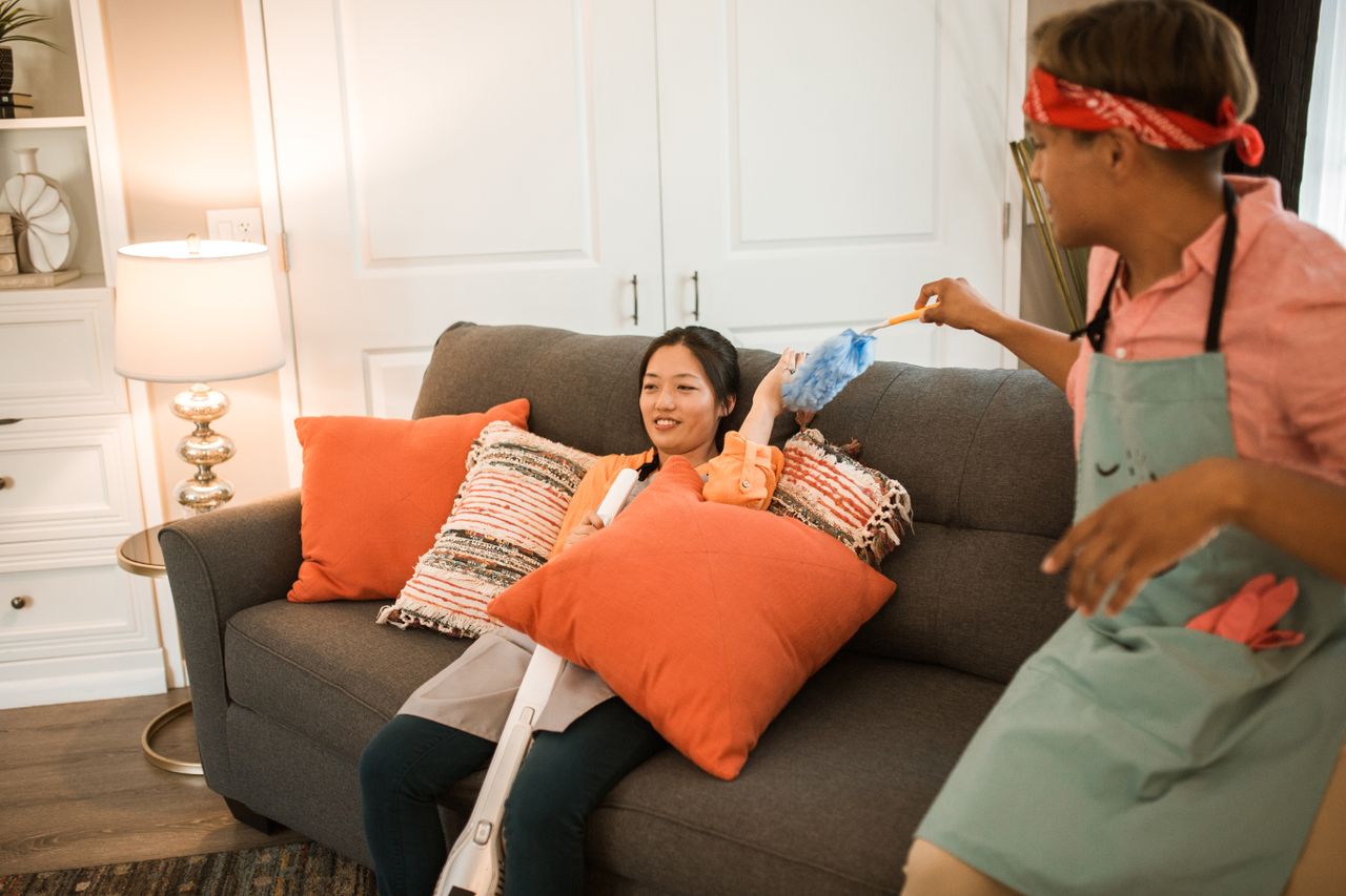 A cheerful couple having fun while playfully cleaning their living room together.